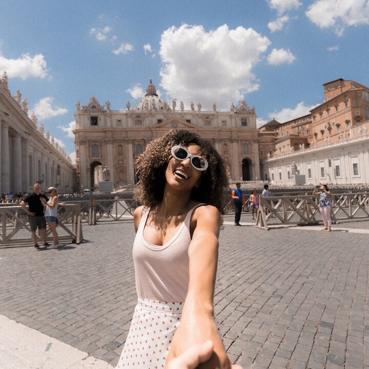 woman holding person's hand near buildings under white and blue cloudy sky